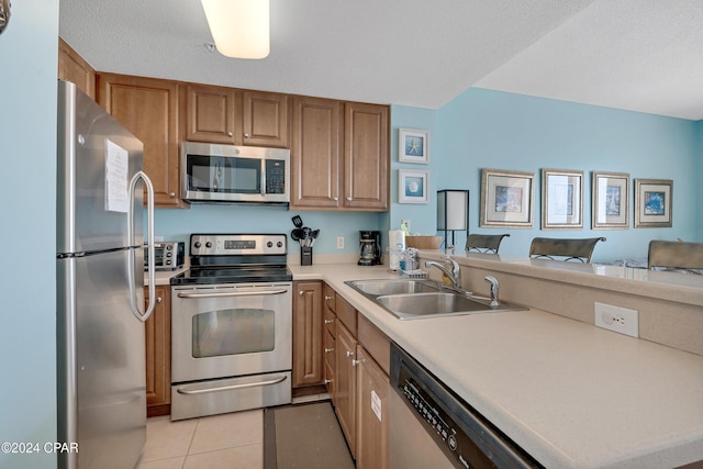 kitchen with light tile patterned floors, stainless steel appliances, kitchen peninsula, and sink