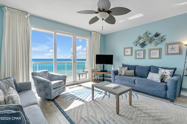 living room with ceiling fan, a textured ceiling, and light hardwood / wood-style floors