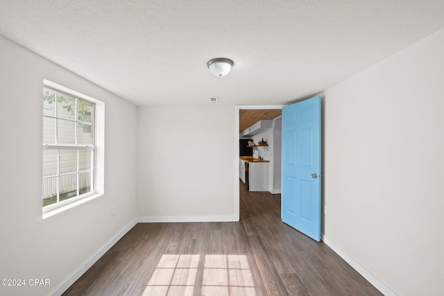 spare room featuring dark hardwood / wood-style flooring and a textured ceiling