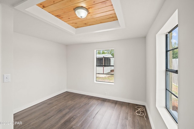 unfurnished room with dark wood-type flooring, a tray ceiling, and wooden ceiling