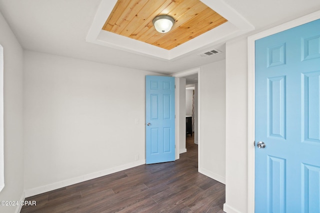 spare room featuring dark wood-type flooring and a raised ceiling