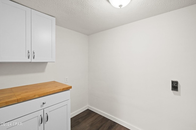 laundry area with a textured ceiling and dark hardwood / wood-style flooring