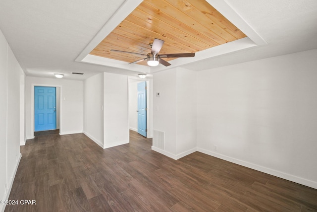 spare room featuring dark wood-type flooring, a tray ceiling, and ceiling fan