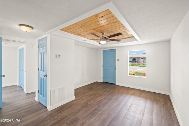 unfurnished room featuring a textured ceiling, dark hardwood / wood-style flooring, ceiling fan, and a tray ceiling