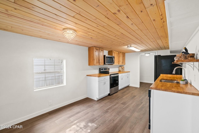 kitchen featuring stainless steel appliances, white cabinetry, wood counters, sink, and light hardwood / wood-style flooring