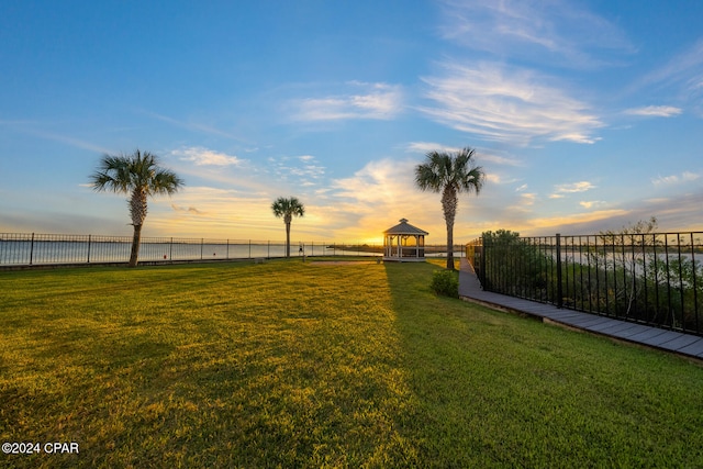 yard at dusk featuring a water view and a gazebo