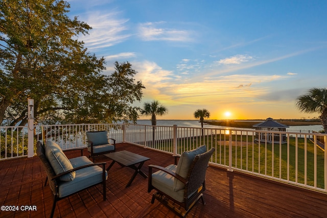 deck at dusk with a water view and a yard