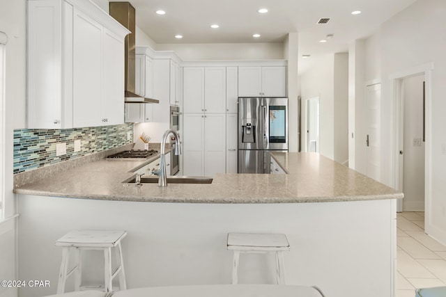 kitchen with appliances with stainless steel finishes, sink, a kitchen breakfast bar, white cabinets, and kitchen peninsula