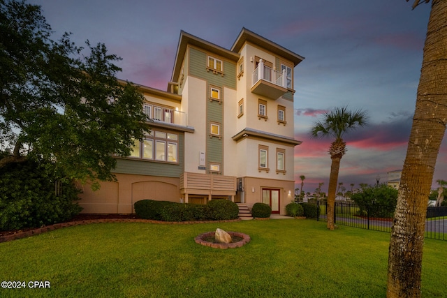 back house at dusk with a lawn and a balcony