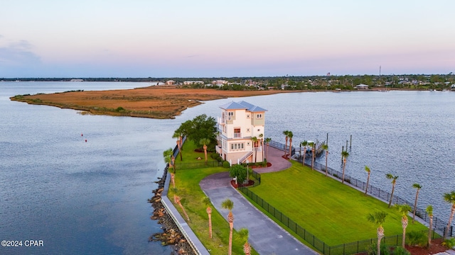 aerial view at dusk featuring a water view