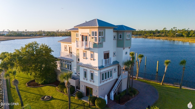 exterior space with a water view, a lawn, and a balcony