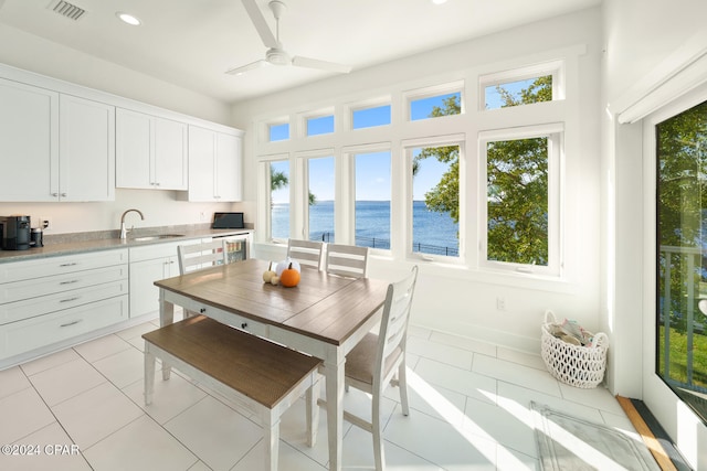 interior space with a water view, ceiling fan, and sink