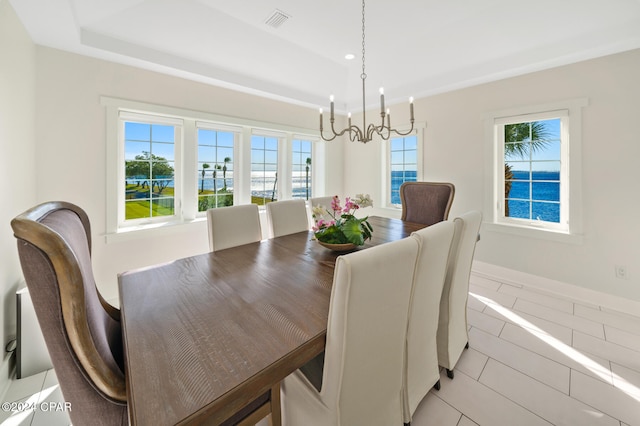 tiled dining room with a water view and a chandelier