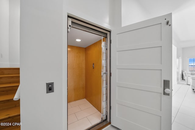 interior details featuring elevator and tile patterned flooring