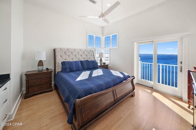 bedroom with access to outside, light hardwood / wood-style flooring, a water view, and ceiling fan