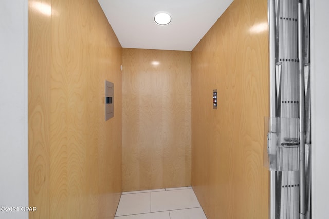 bathroom with wood walls, elevator, and tile patterned flooring