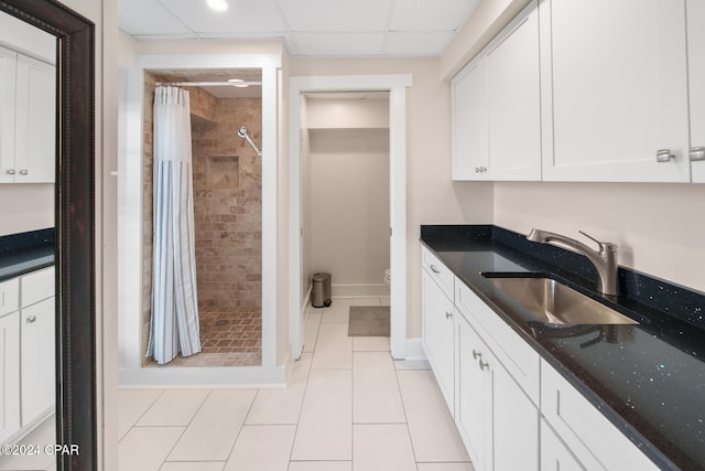 kitchen featuring dark stone countertops, sink, light tile patterned floors, and white cabinets