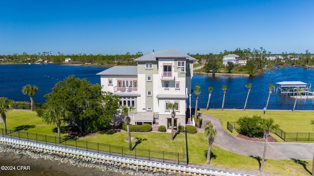 exterior space featuring a front lawn, a balcony, and a water view