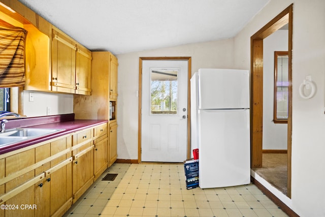 kitchen featuring sink, white refrigerator, and vaulted ceiling