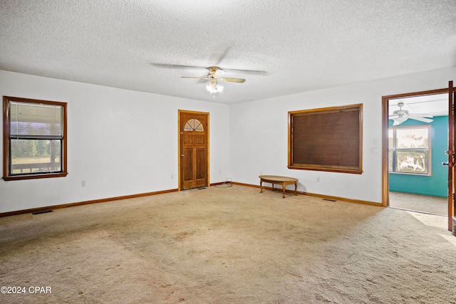 carpeted empty room with ceiling fan and a textured ceiling