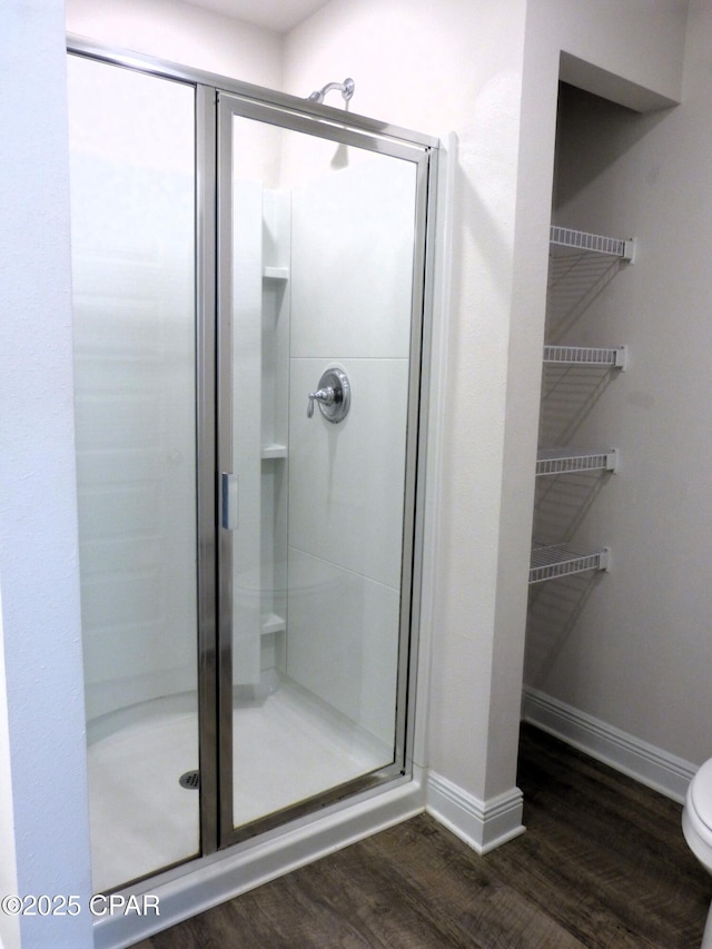 bathroom featuring hardwood / wood-style floors, a shower with door, and toilet