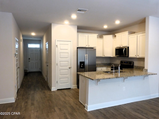 kitchen featuring a breakfast bar area, appliances with stainless steel finishes, light stone counters, white cabinets, and kitchen peninsula