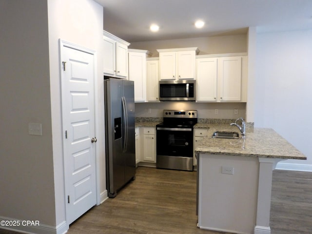 kitchen with white cabinetry, light stone counters, stainless steel appliances, and kitchen peninsula