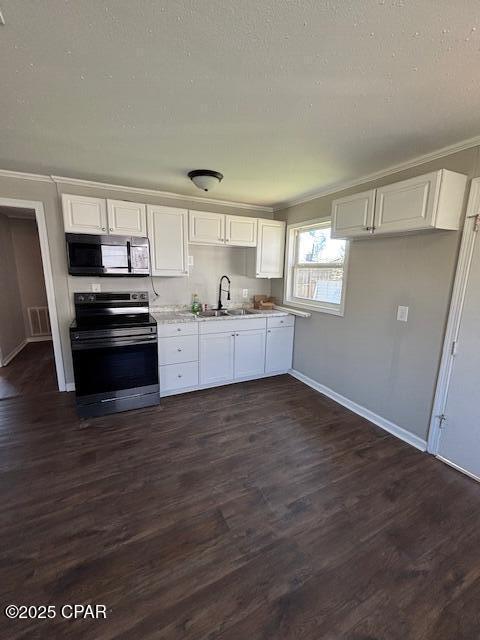 kitchen with stainless steel electric range oven, light countertops, white cabinets, a sink, and black microwave