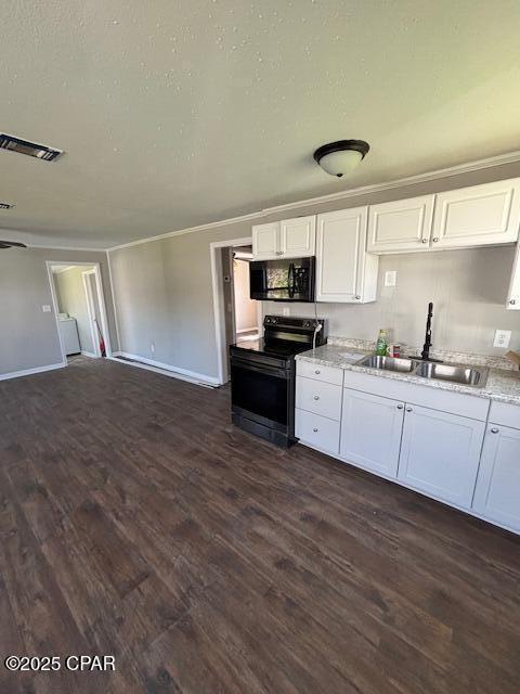 kitchen with stainless steel electric range oven, light countertops, white cabinetry, a sink, and black microwave