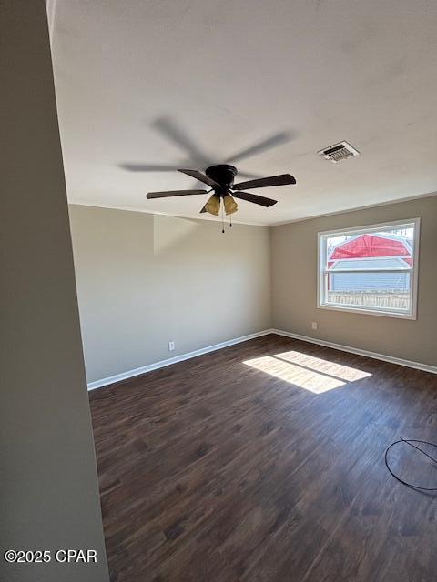 unfurnished room with baseboards, visible vents, dark wood finished floors, and a ceiling fan