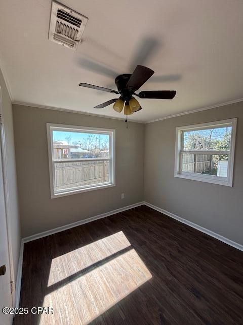 spare room featuring visible vents, dark wood-style flooring, and ornamental molding