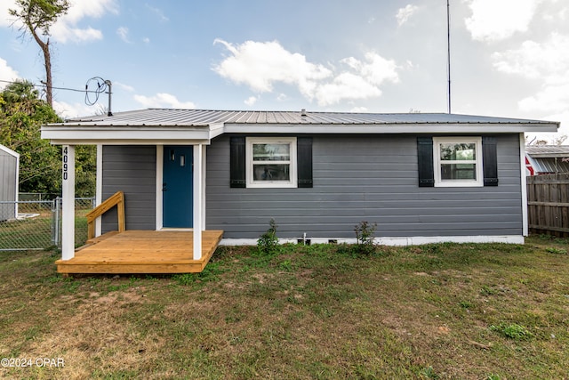 view of front facade with metal roof, fence, and a front lawn