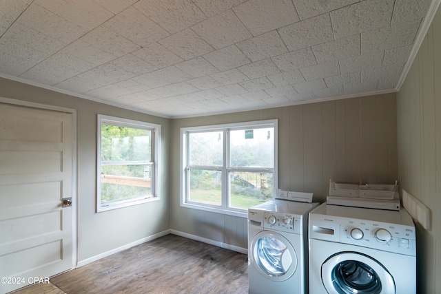 laundry room featuring laundry area, wood finished floors, washing machine and dryer, and crown molding