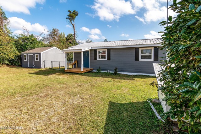 rear view of house with a storage unit and a yard