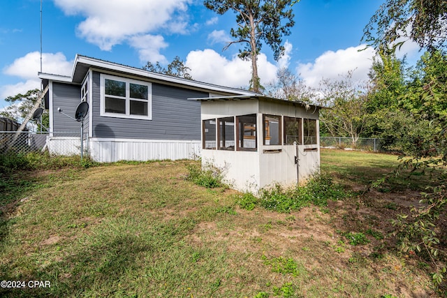 view of home's exterior featuring a sunroom and a yard