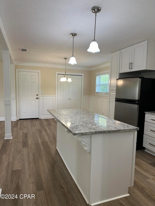 kitchen featuring dark wood-type flooring, hanging light fixtures, stainless steel fridge, light stone countertops, and white cabinetry