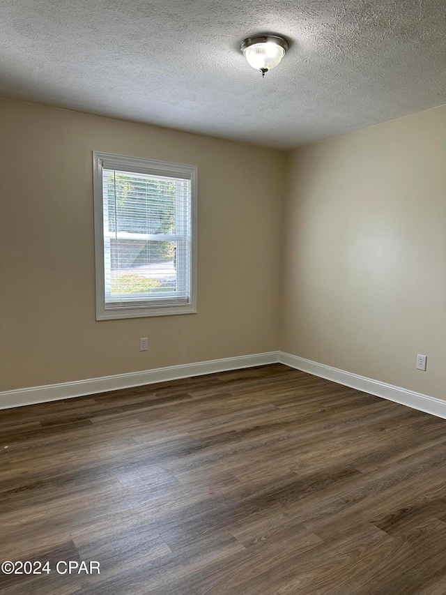 spare room with a textured ceiling and dark wood-type flooring