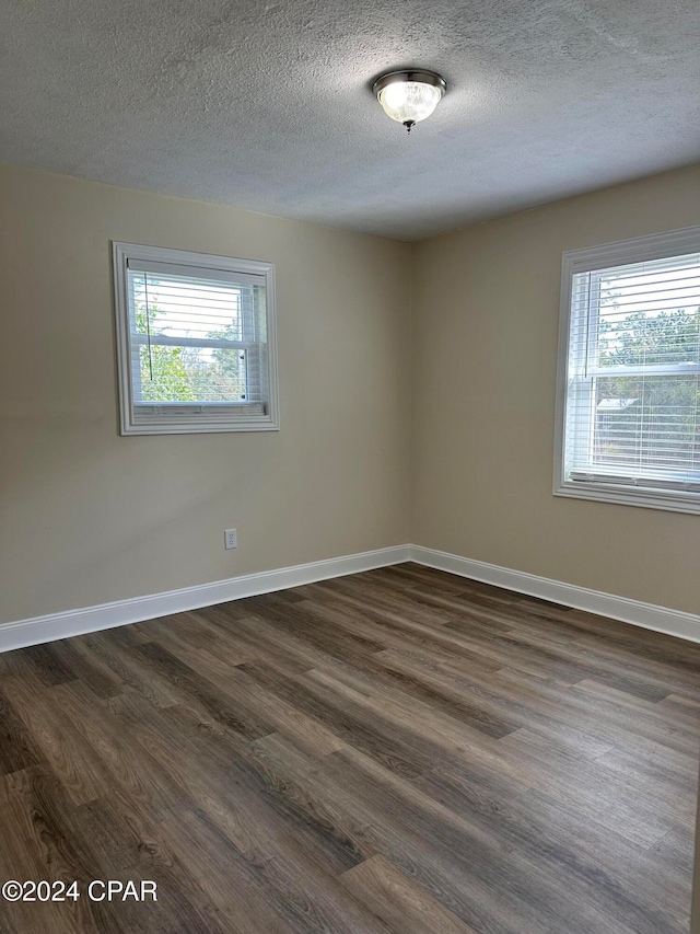 spare room with a textured ceiling and dark hardwood / wood-style floors