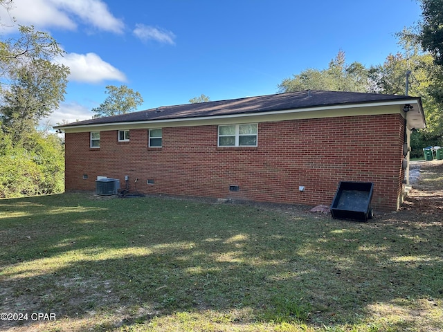 rear view of house featuring a lawn and central AC unit