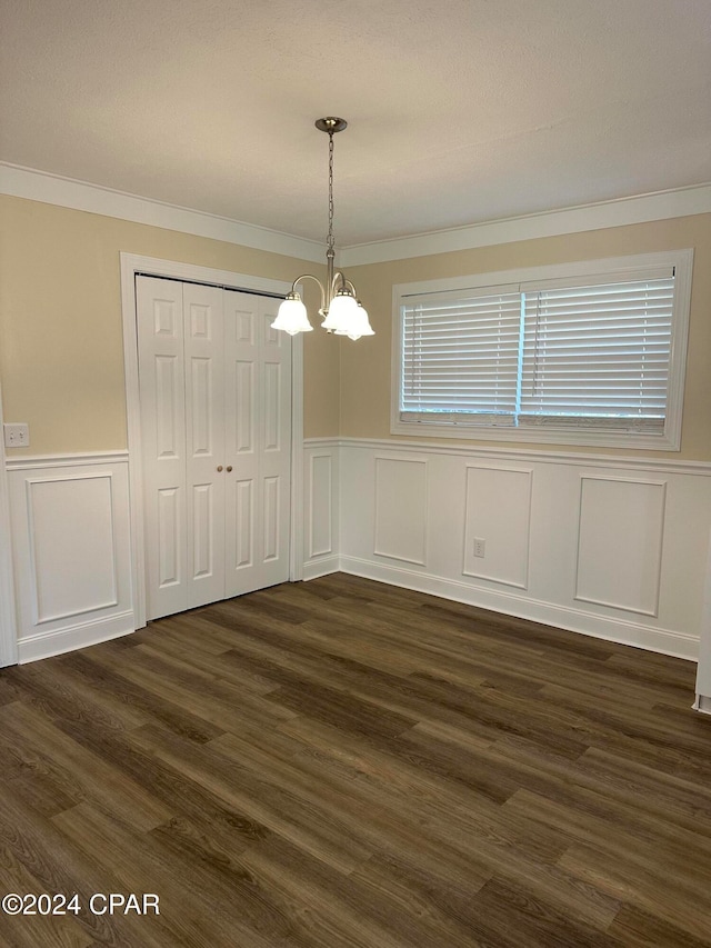 unfurnished dining area with dark hardwood / wood-style flooring, crown molding, and a chandelier