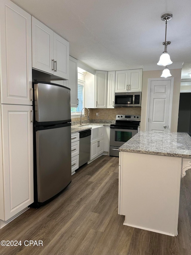 kitchen with decorative light fixtures, stainless steel appliances, white cabinetry, and dark hardwood / wood-style floors