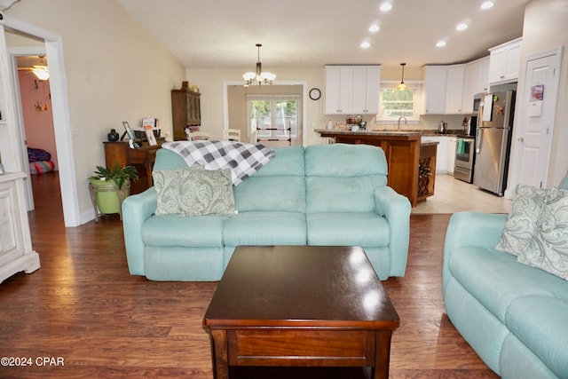 living room with ceiling fan with notable chandelier, wood-type flooring, and sink