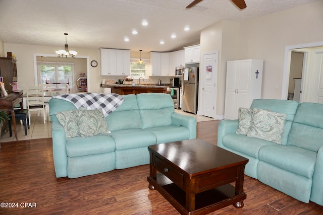 living room featuring lofted ceiling, dark hardwood / wood-style floors, sink, and ceiling fan with notable chandelier