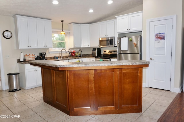 kitchen featuring appliances with stainless steel finishes, hanging light fixtures, a kitchen island, and vaulted ceiling