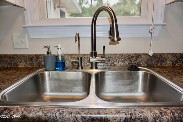 interior details featuring white cabinetry, sink, and dark stone countertops