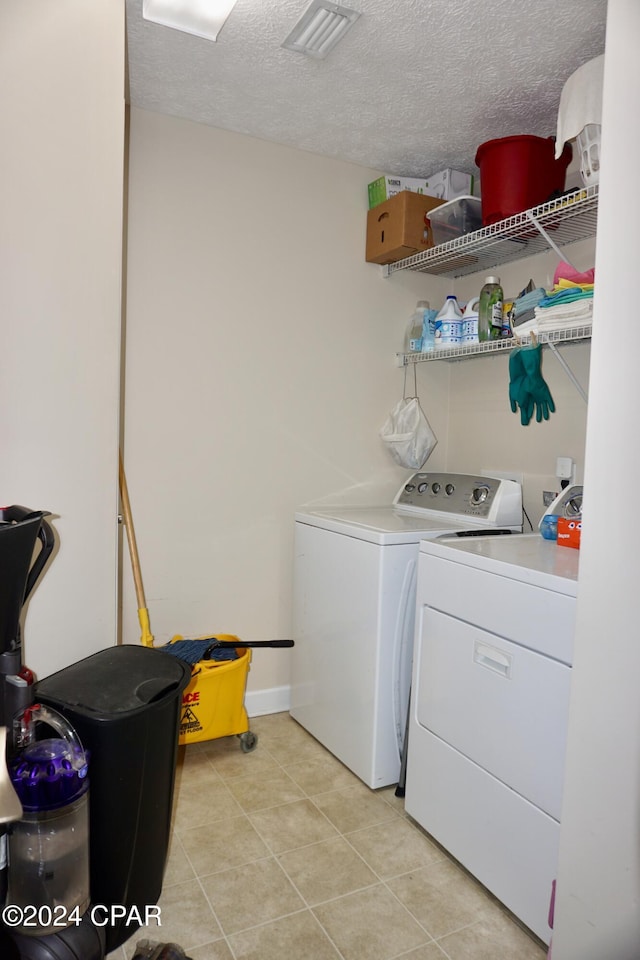 laundry room featuring a textured ceiling, washer and dryer, and light tile patterned floors