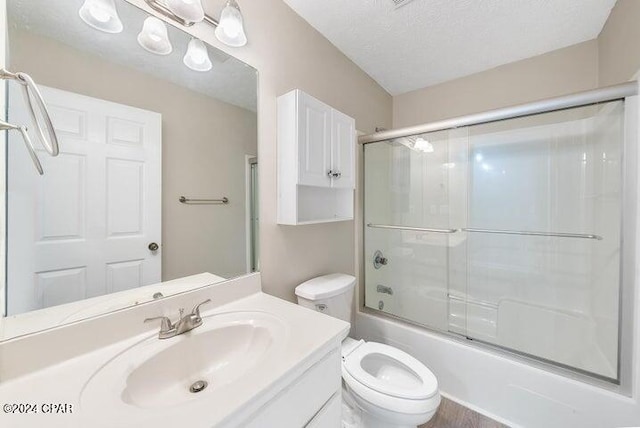 full bathroom with toilet, vanity, bath / shower combo with glass door, and a textured ceiling