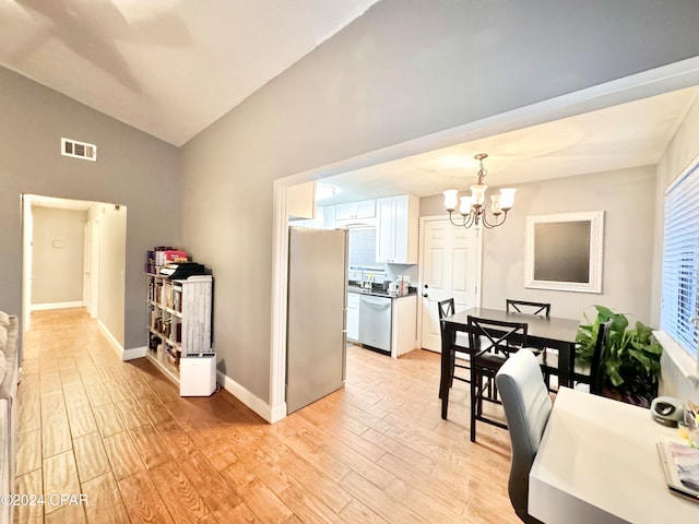 kitchen featuring stainless steel appliances, light hardwood / wood-style floors, decorative light fixtures, vaulted ceiling, and white cabinets