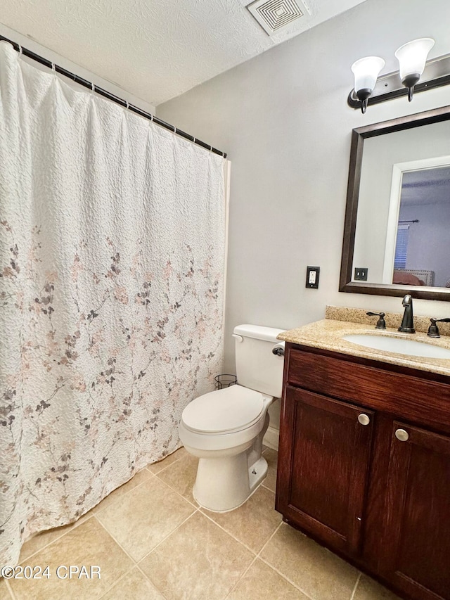 bathroom featuring tile patterned flooring, vanity, a textured ceiling, and toilet