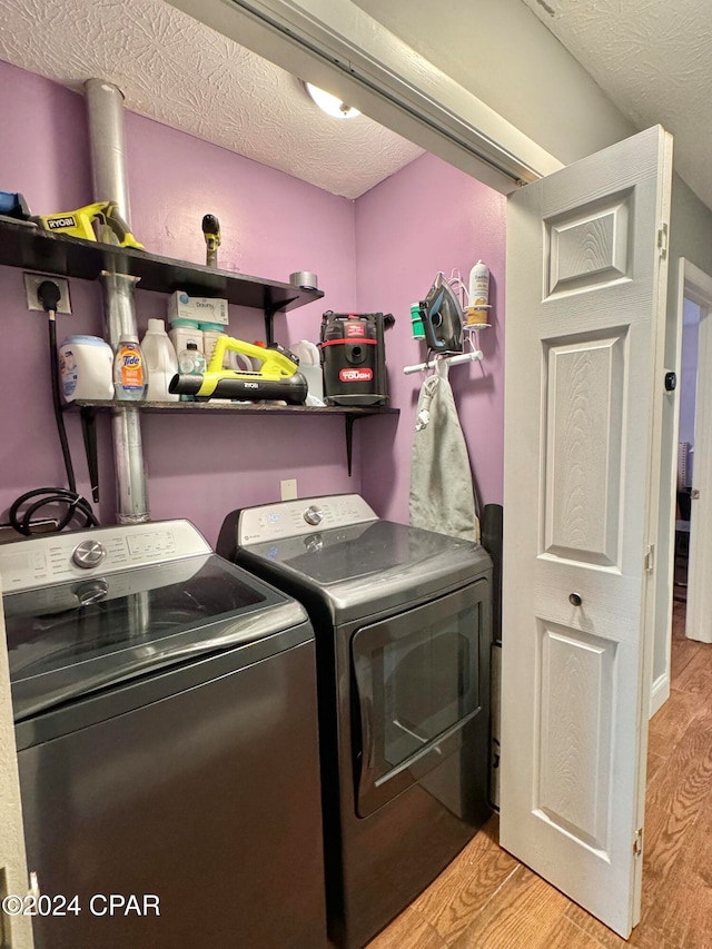 washroom with a textured ceiling, light hardwood / wood-style flooring, and washing machine and dryer